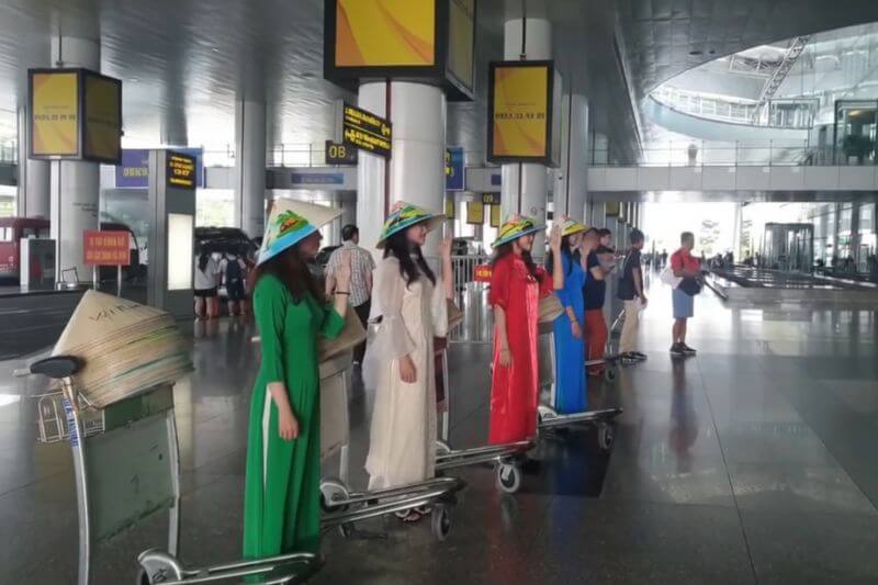 Dong DMC welcome team in Vietnam arrivals hall with partner-branded group signage and flight code